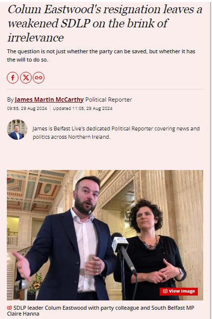 SDLP leader Colum Eastwood speaks at a podium beside party colleague and South Belfast MP Claire Hanna inside a government building.