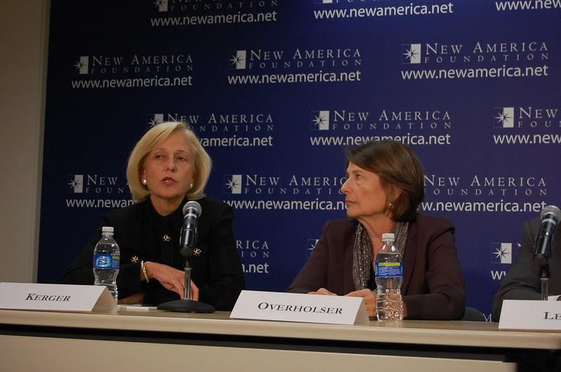 Two women sit at a panel table with microphones and water bottles, speaking at an event hosted by the New America Foundation.
