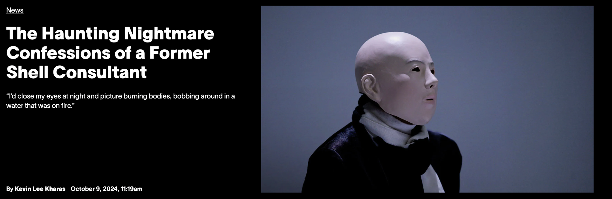 A person wearing a white, expressionless mask and dark clothing stands against a plain, muted background.