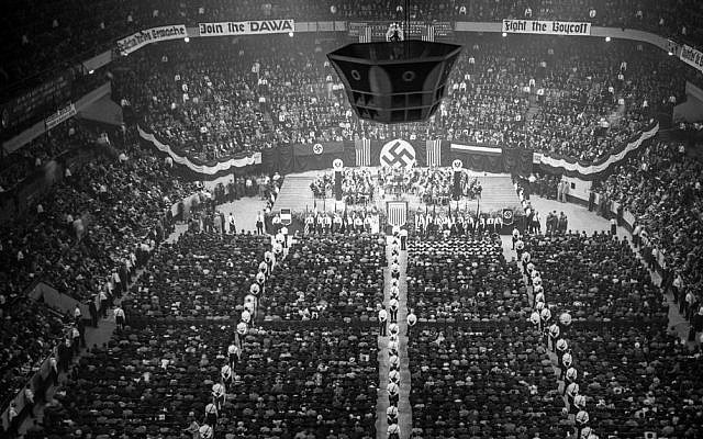 A large indoor Nazi rally with banners, swastika symbols, and a speaker at a podium, surrounded by a crowd seated in an arena.