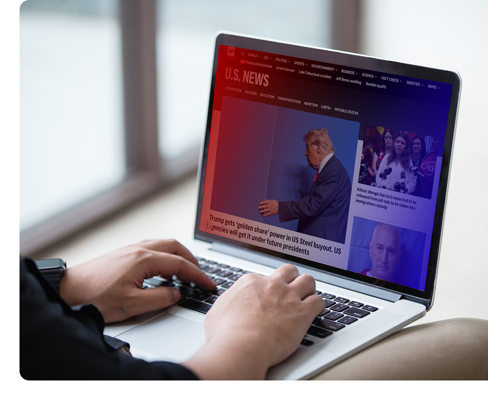 Person using a laptop displaying a U.S. news website with articles and images, including a prominent image of a man in a suit and political news headlines.