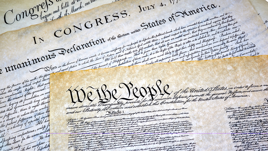 Close-up of historic U.S. documents, including the Declaration of Independence and the Constitution, showing distinctive handwritten text and aged paper.