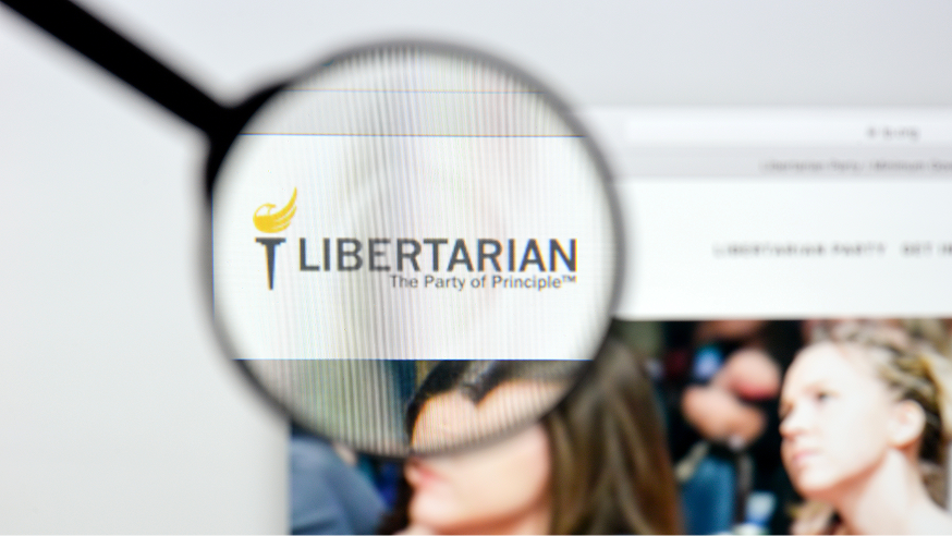 A magnifying glass focuses on the Libertarian Party logo and slogan, “The Party of Principle,” displayed on a computer screen.